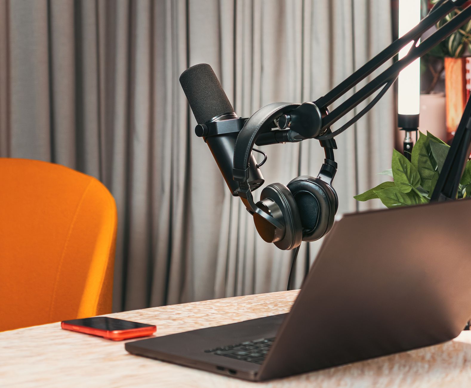 A desk with laptop, notebook, pen, phone and voice recorder